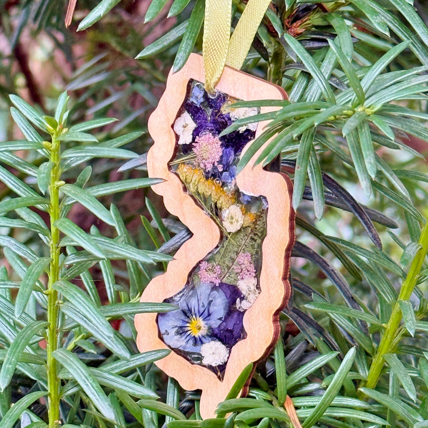 Christmas ornament in the shape of New Jersey filled with real flowers in resin
