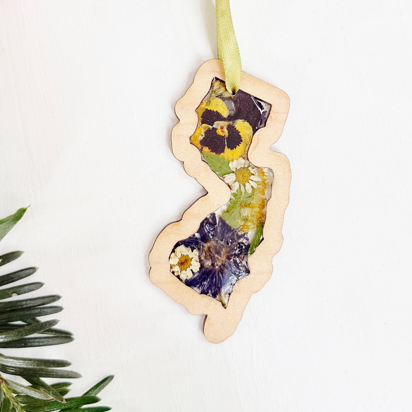 Christmas ornament in the shape of New Jersey filled with real flowers in resin